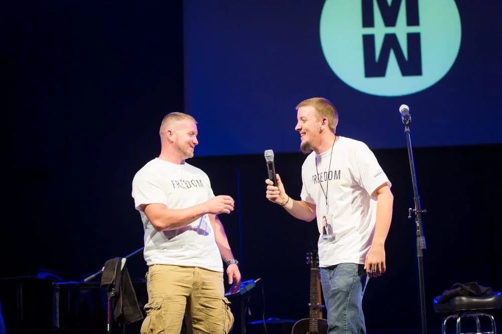 Justin handing microphone to Teen Challenge student at Matthew West concert