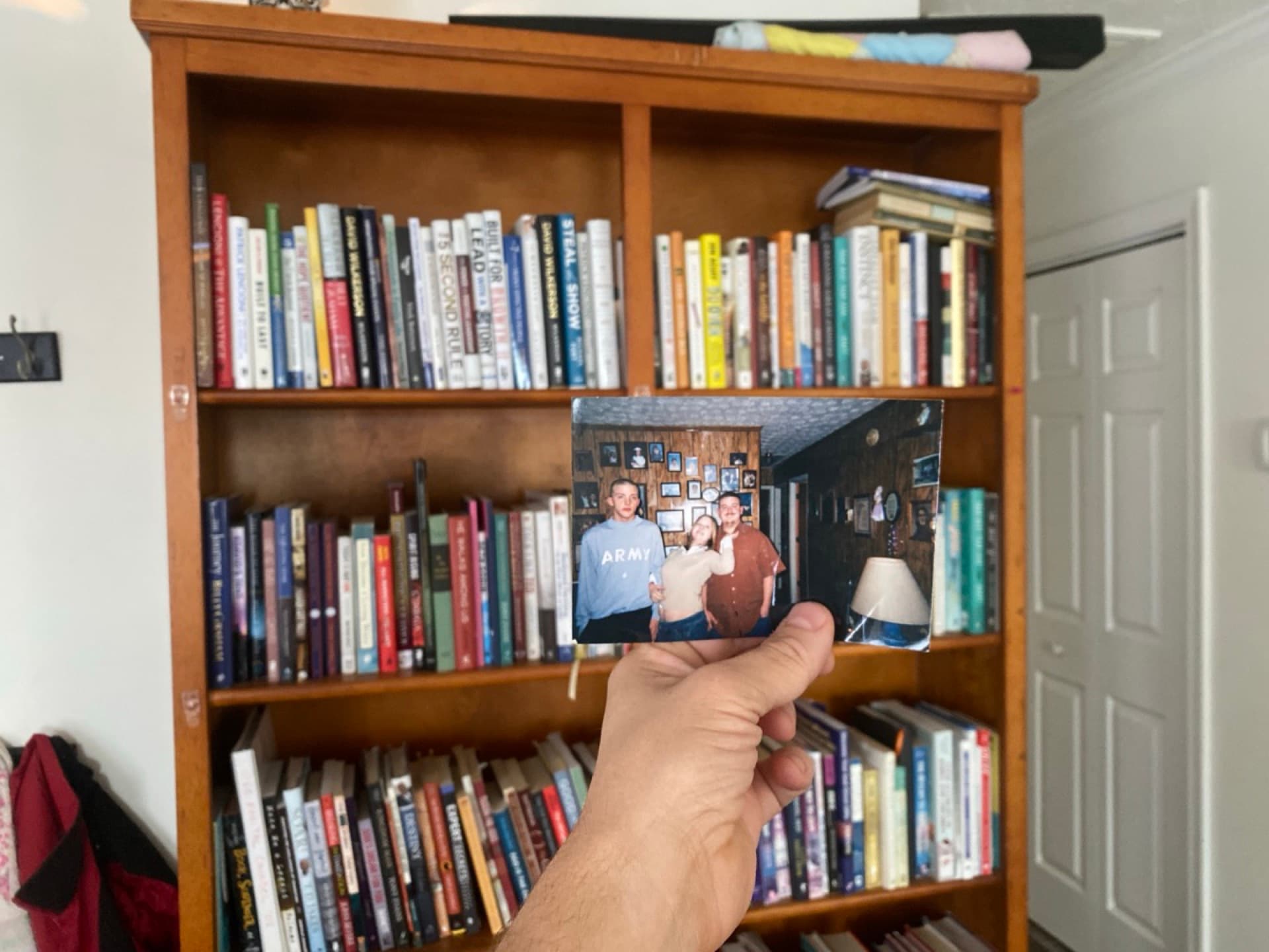 Justin Franich holding an old Army family photo in front of a bookshelf