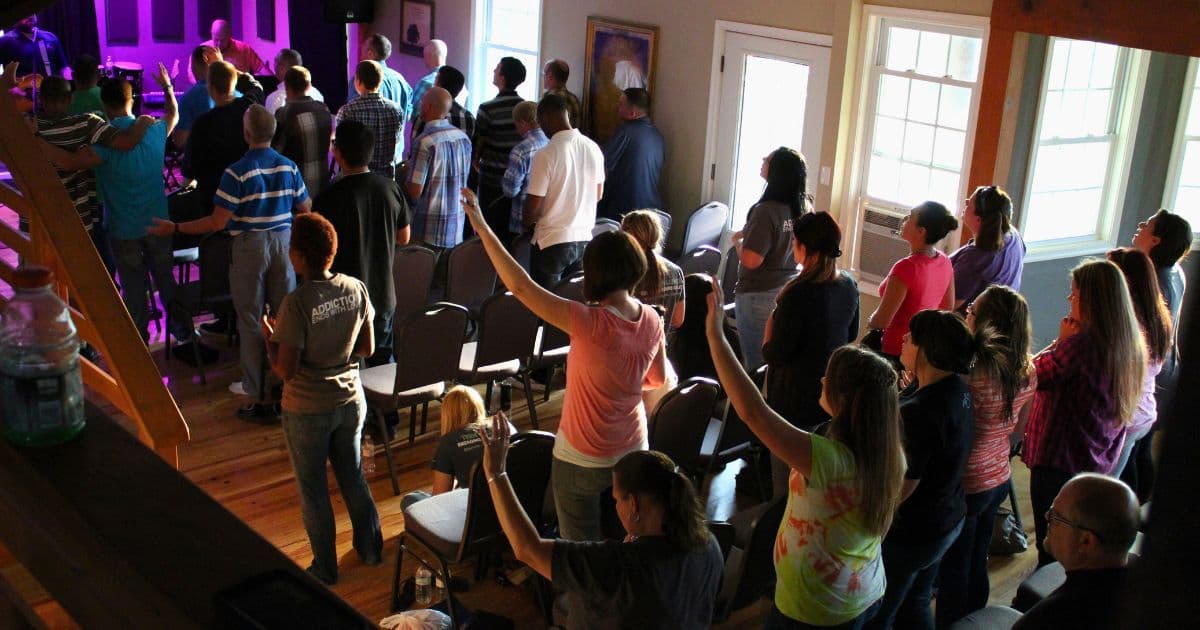 A room full of people standing in worship during a chapel service at a faith-based recovery program