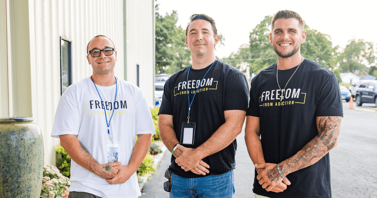 Three men in Teen Challenge Freedom From Addiction shirts standing outside the Shenandoah Valley facility